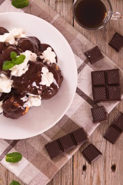 Beyaz çanak üzerinde çikolatalı profiterol.