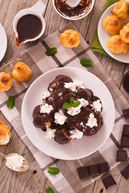 Beyaz çanak üzerinde çikolatalı profiterol.