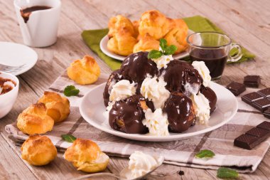 Beyaz çanak üzerinde çikolatalı profiterol.