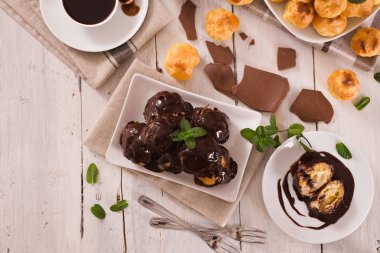 Beyaz çanak üzerinde krema ile çikolata profiteroller.