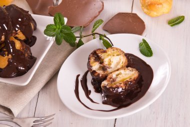 Beyaz çanak üzerinde krema ile çikolata profiteroller.