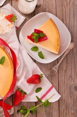 Ahşap masa üzerinde nane ile Çilek cheesecake.