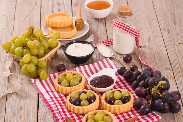 Grape tarts with jam on wooden table.