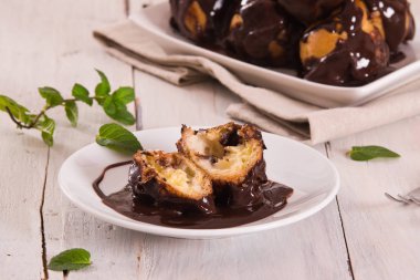 Beyaz çanak üzerinde krema ile çikolata profiteroller.