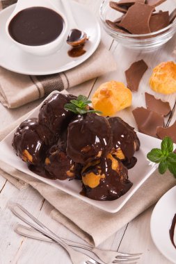 Beyaz çanak üzerinde krema ile çikolata profiteroller.