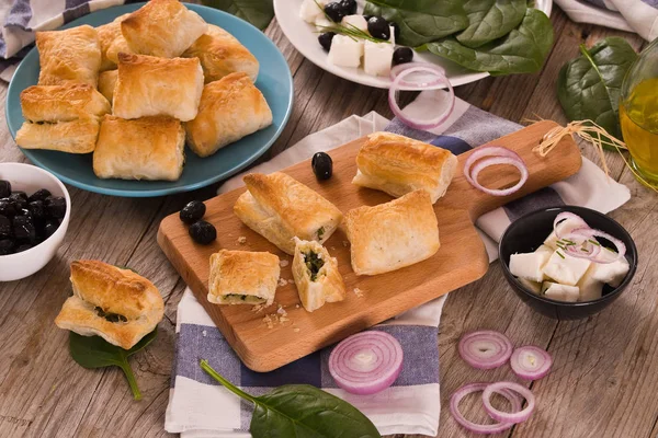 Kesme tahtası üzerinde beyaz peynir ile ıspanak puffs.