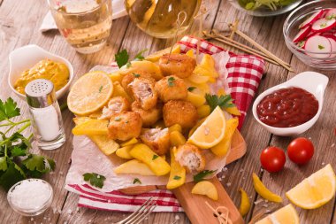 Kesme tahtası üzerinde maydanoz ile balık ve cips.