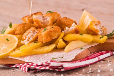 Kesme tahtası üzerinde maydanoz ile balık ve cips.