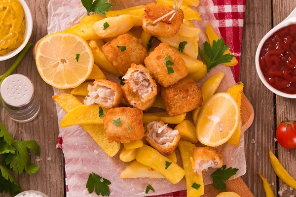 Kesme tahtası üzerinde maydanoz ile balık ve cips.