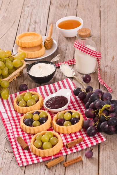 Grape tarts with jam on wooden table.