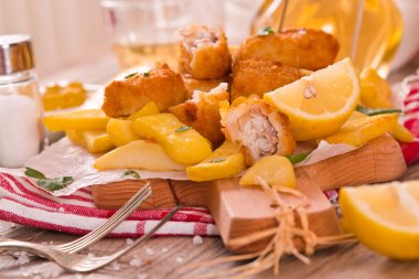 Kesme tahtası üzerinde soslu balık ve cips.