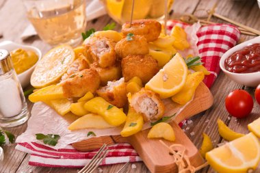 Kesme tahtası üzerinde soslu balık ve cips.