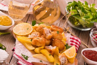 Kesme tahtasında patates kızartması ile balık ve cips.