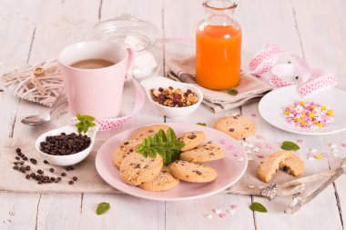 Beyaz tabakta kapuçino olan çikolata parçacıklı kurabiyeler..