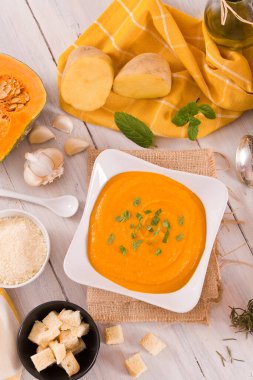 Beyaz tabakta balkabağı kremalı çorba.