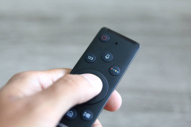 bir uzaktan kumanda ile kanalları açık gri arka planı üzerinde değişen el