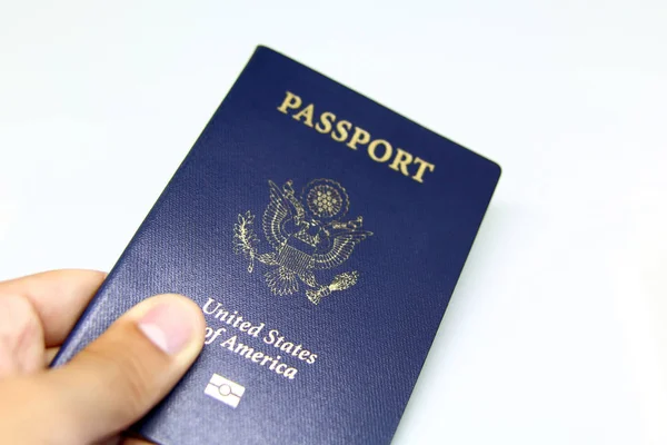 Image of a persons hand holding a passport over a white background