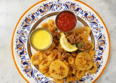 Kızarmış kalamar halkaları ve limon calacatta mermer counterto üzerinden güzel bir İspanyol seramik plaka üzerinde