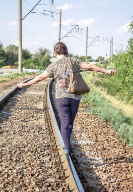 Bir kadın tren yolunda yürüyor.