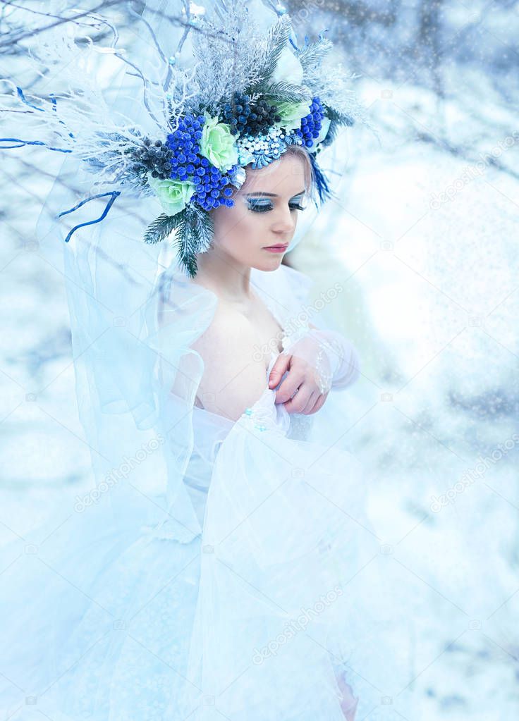 beautiful winter fairy in crown and light blue dress walking over snow field Snow Queen concept