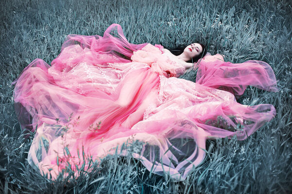 Sleeping beautiful young woman from fairy tale lying on silver grass