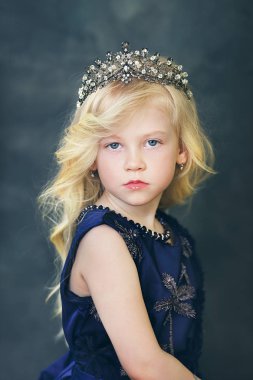 koyu mavi elbise giymiş ve kafasına taç ile sarı saçlı güzel küçük kız