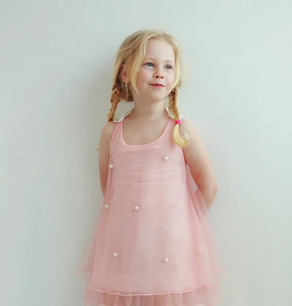 桃ピンクのドレスで2つのピグテールを持つ美しい小さな女の子 — ストック写真