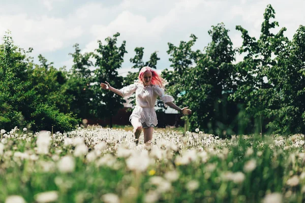 Une fille court à travers un champ de pissenlits en été — Photo