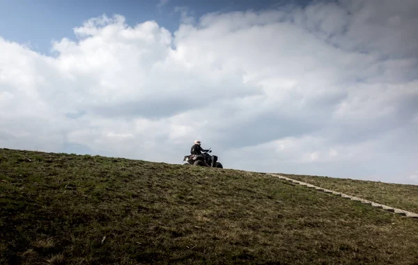 Riding a quad bike on the lake dam — Stock Photo, Image