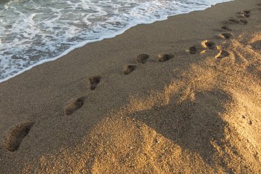 Ayak izleri İspanya'nın Calella bölgesinde plaj kumüzerinde deniz suyu ile sular altında