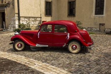 Tyniec, Krakow, Polonya, 3 Ağustos 2019: Düğünde yeni evlileri taşımak için kullanılan eski, antika kırmızı araba, Polonya 'nın Krakow yakınlarındaki Tyniec kilisesinin önünde duruyordu..