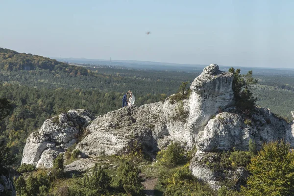 A pair of newlyweds during a photo session on the rocks against — Stock Photo, Image