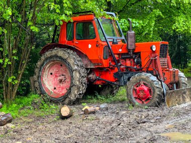 Tekerleklerinde zincirler olan kırmızı bir traktör Polonya 'daki Bieszczady Dağları' ndaki dağlık koşullarda orman çalışmaları için adapte olmuştur..