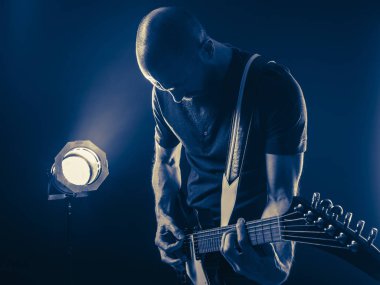 Bir gitarist Spot arka plan olarak karanlık bir kulüpte oynamaktan sakallı fotoğrafı.