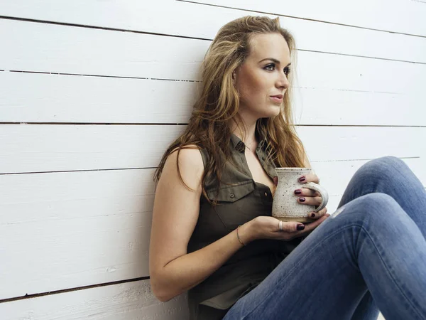 飲むコーヒー傾いた木製の壁 美しい若い女性の写真 — ストック写真