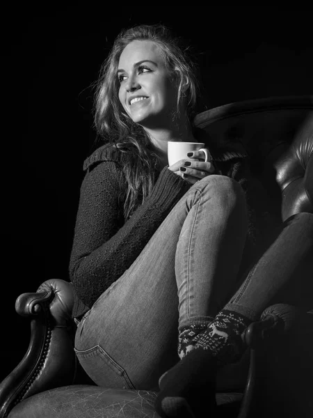古い革張りの椅子に座って珈琲を飲んで美しい若い女性の写真 — ストック写真