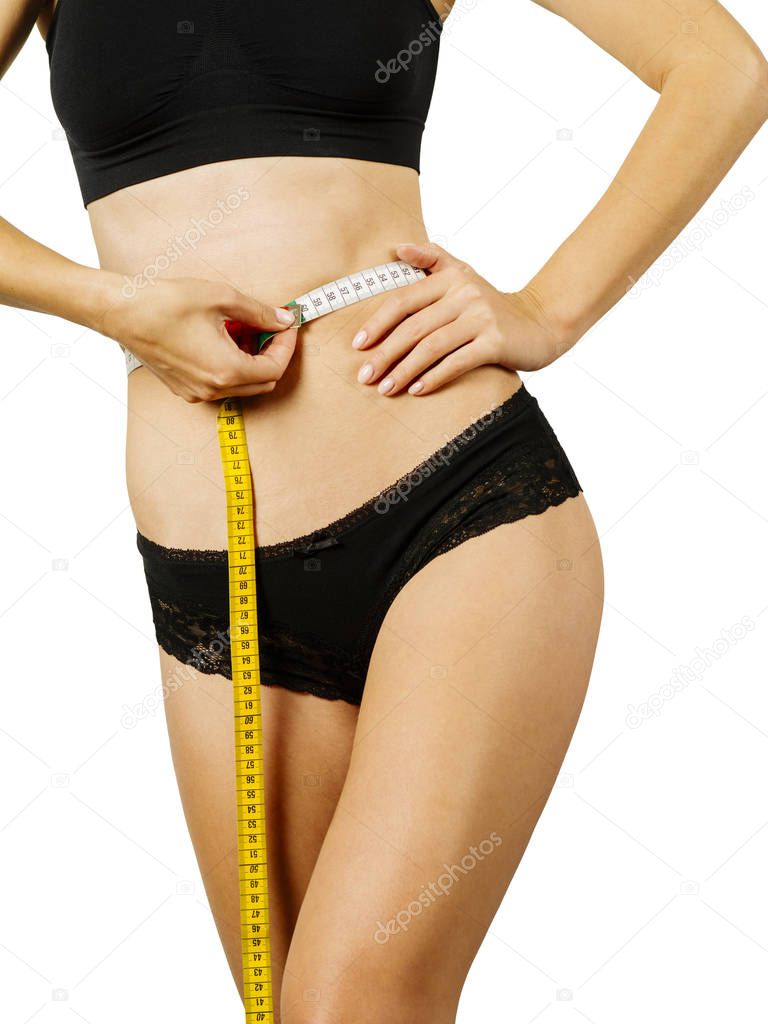 Photo of a slim young woman measuring her waistline over white background.