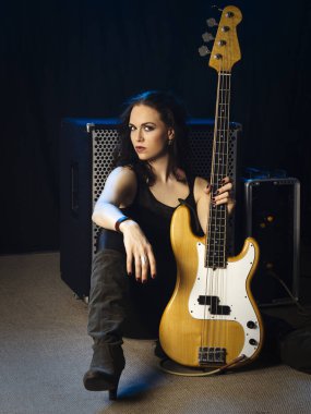 Onun amplifikatör önünde oturan bir güzel kadın bas gitarist fotoğrafı