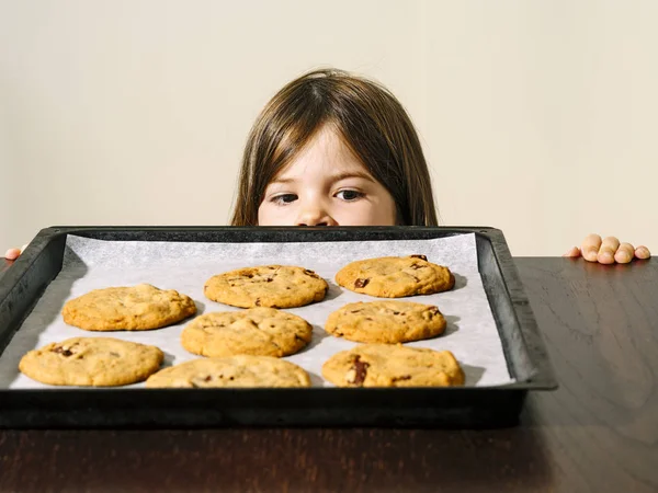 Fotografie Mladé Dívky Zírající Tác Teplými Čokoládovými Sušenkami Právě Vytaženými — Stock fotografie