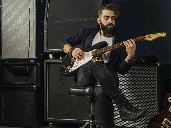Skäggig man spelar en elgitarr i en studio — Stockfoto