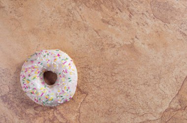 Kahverengi taş arka plan, metin için yer ile üstten görünüm üzerinde renkli sprinkles ile sırlı çörek