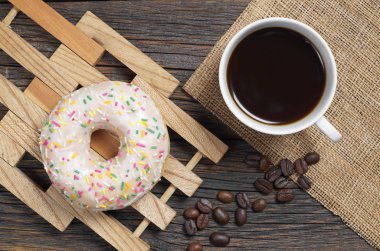 Fincan kahve ve tatlı çörek buzlanma ile ve renkli eski ahşap masa, üstten görünüm 