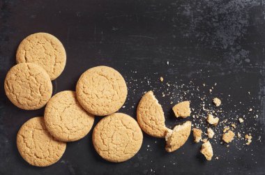 Yulaf ezmeli kurabiye ve kırıntıları eski siyah metal arka planda üstten görünüm