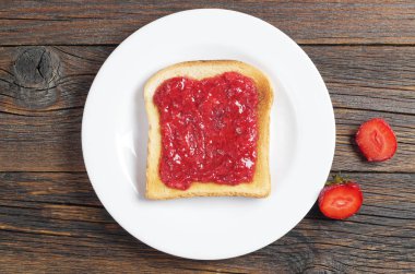 Koyu ahşap masa, üstten görünüm tabağa çilek reçelli ekmek dilim tost
