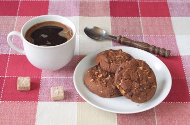 Sıcak kahve ve çikolata kurabiye fındık damalı bir masa örtüsü ile fincan  