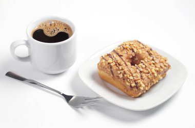 Fincan kahve ve karamel bir sır ile kare çörek kavrulmuş fındık ve beyaz arka plan üzerinde çikolata çizgiler ile dekore edilmiştir