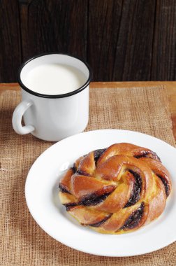 Topuz ile çikolatalı krema ve emaye bir fincan süt rustik ahşap masa üzerinde