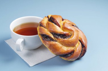 Çikolata kremalı çörek ve çay mavi masada kahvaltı için Kapat