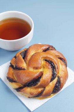 Çikolata kremalı çörek ve çay mavi masada kapat