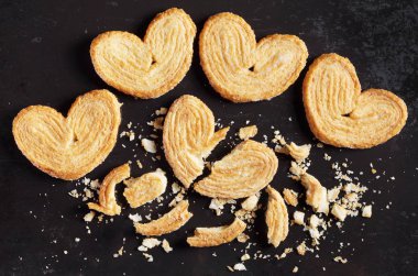 Görünüm Palmiers, bütün ve kırık puf böreği çerez eski siyah metal arka planda, top